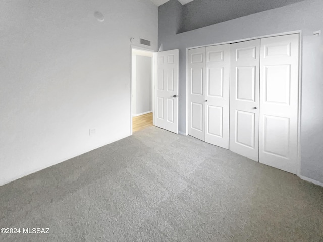 unfurnished bedroom with light colored carpet and a closet