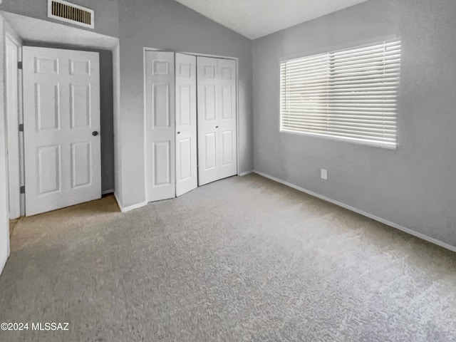 unfurnished bedroom with a closet, light colored carpet, and vaulted ceiling