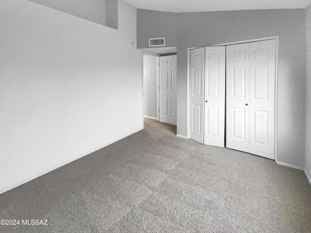 unfurnished bedroom with carpet flooring, lofted ceiling, and a closet