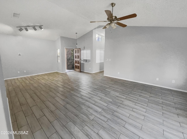 unfurnished living room with a textured ceiling, ceiling fan, light hardwood / wood-style floors, and vaulted ceiling