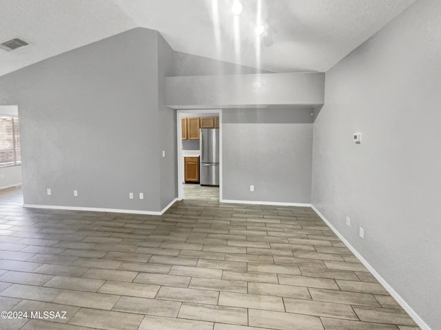 interior space featuring a textured ceiling, light hardwood / wood-style flooring, and lofted ceiling