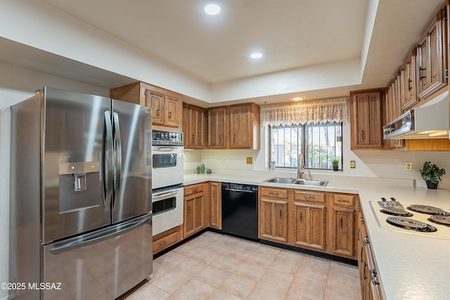 kitchen with white appliances, range hood, and sink