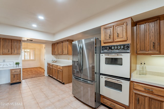 kitchen featuring double oven, stainless steel fridge with ice dispenser, light tile patterned floors, and an inviting chandelier