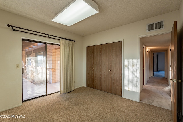 unfurnished bedroom featuring carpet, a textured ceiling, and a closet