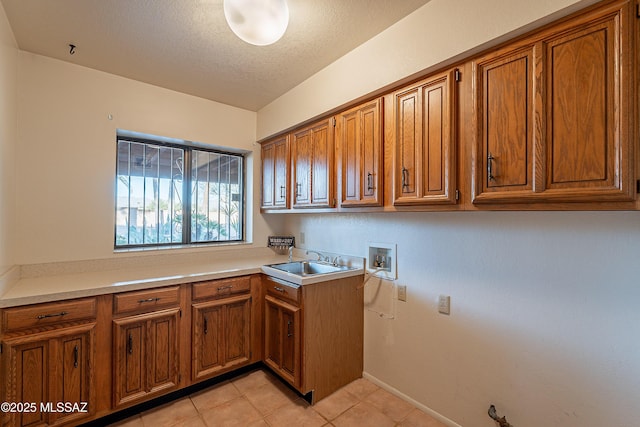 clothes washing area with cabinets, sink, hookup for a washing machine, a textured ceiling, and light tile patterned flooring