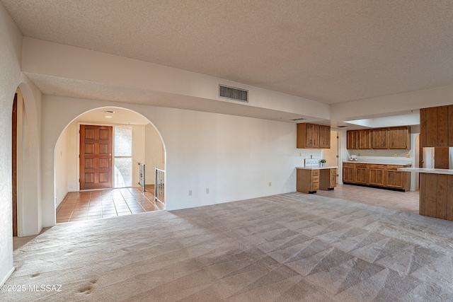 unfurnished living room with light carpet and a textured ceiling