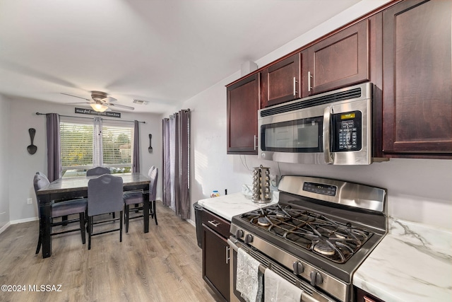 kitchen featuring ceiling fan, stainless steel appliances, light stone counters, and light hardwood / wood-style floors