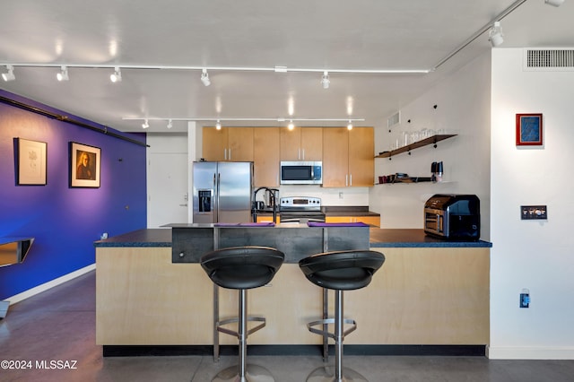 kitchen featuring stainless steel appliances, a breakfast bar, and track lighting