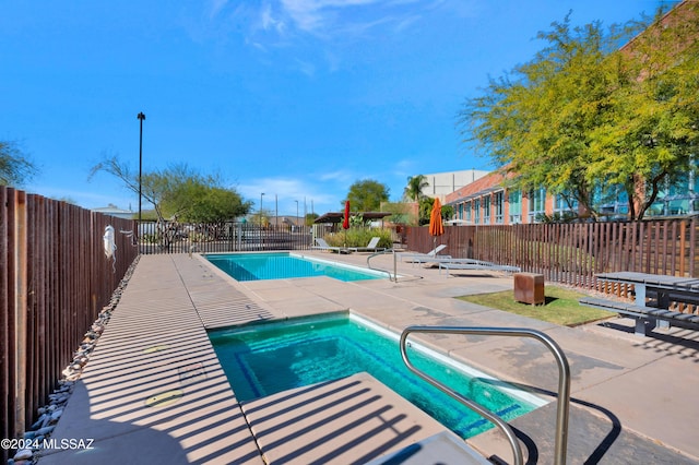 view of pool featuring a patio and an in ground hot tub