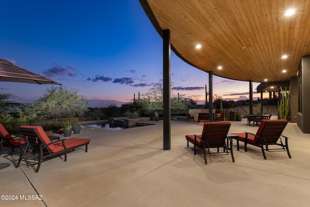 patio terrace at dusk featuring a swimming pool with hot tub