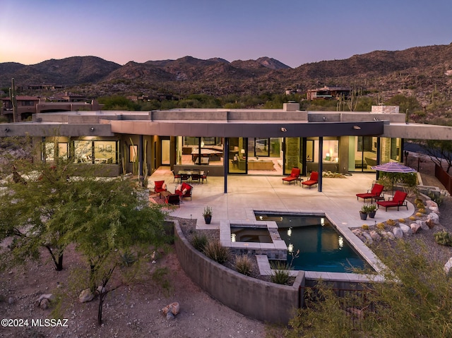 back house at dusk with a mountain view and a patio area