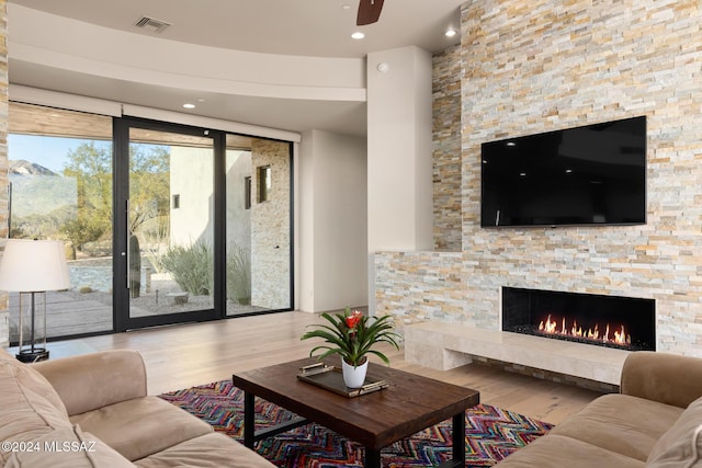 living room with ceiling fan, a fireplace, and light hardwood / wood-style floors