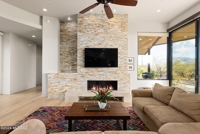 living room featuring ceiling fan, a fireplace, and light hardwood / wood-style floors