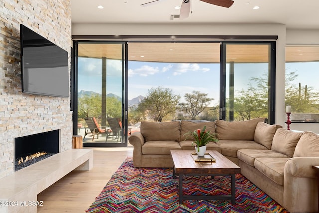 living room featuring a fireplace, light wood-type flooring, and ceiling fan