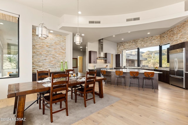 dining space with sink, a towering ceiling, and light hardwood / wood-style floors