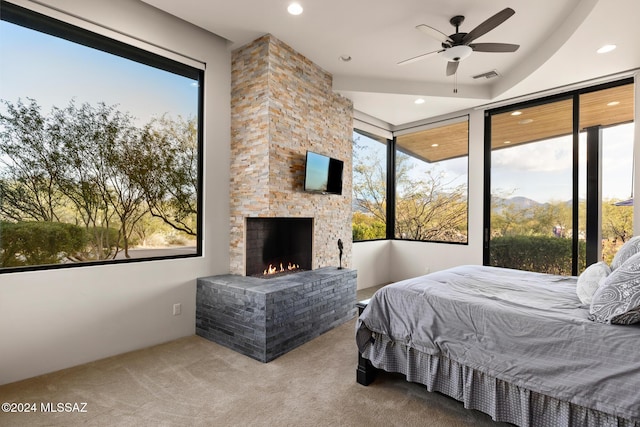 bedroom featuring carpet, a stone fireplace, and ceiling fan