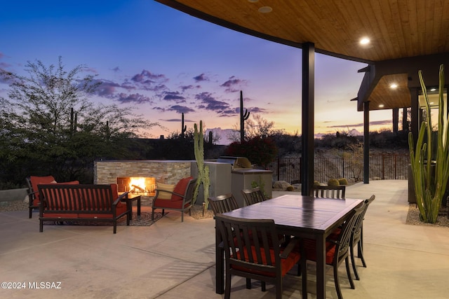 patio terrace at dusk featuring outdoor lounge area and an outdoor kitchen