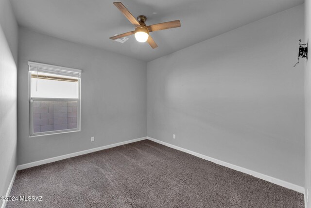 empty room with ceiling fan and dark carpet