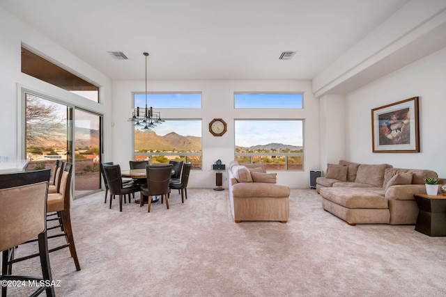 carpeted living room with a mountain view, a healthy amount of sunlight, and an inviting chandelier