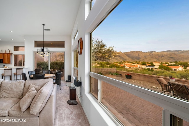 sunroom / solarium with a mountain view, an inviting chandelier, and a healthy amount of sunlight