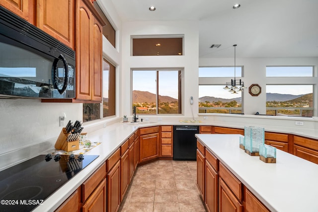 kitchen featuring sink, a mountain view, decorative light fixtures, light tile patterned floors, and black appliances