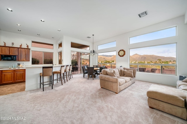 living room with a mountain view, a towering ceiling, light carpet, and a notable chandelier