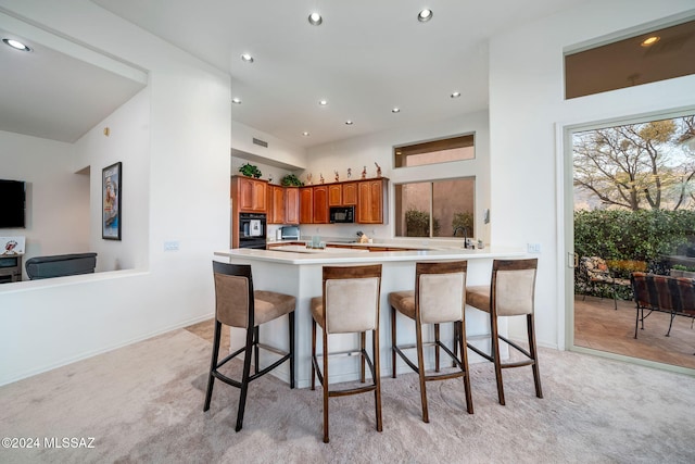 kitchen with kitchen peninsula, a breakfast bar, and light colored carpet