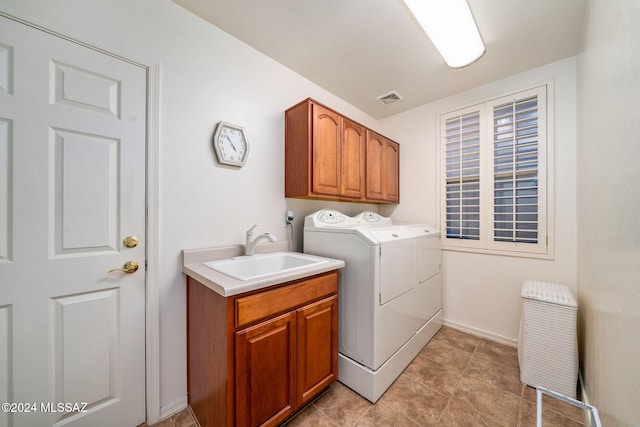 laundry area featuring washing machine and clothes dryer, sink, light tile patterned flooring, and cabinets