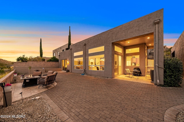 back house at dusk featuring a fire pit and a patio area