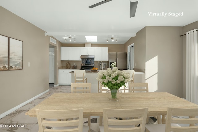 dining room featuring a skylight, sink, and rail lighting