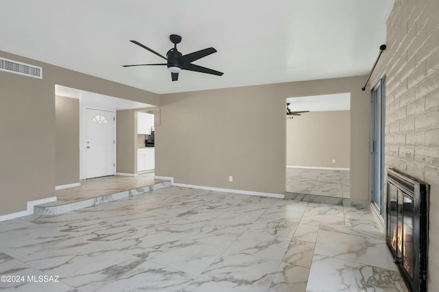 unfurnished living room featuring ceiling fan and a large fireplace