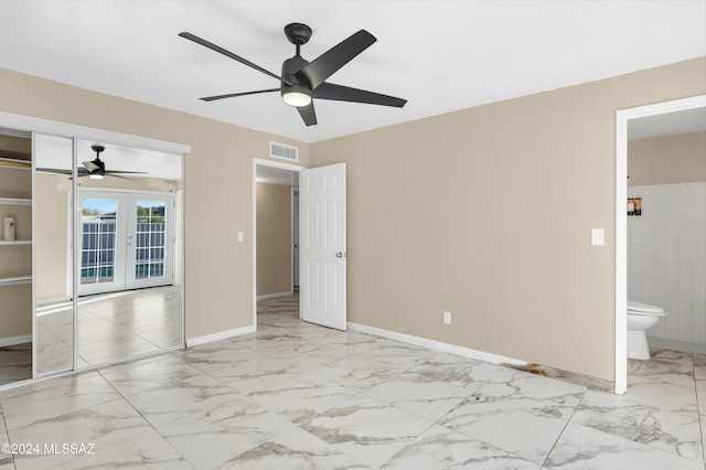 unfurnished bedroom with french doors, a closet, ensuite bathroom, and ceiling fan