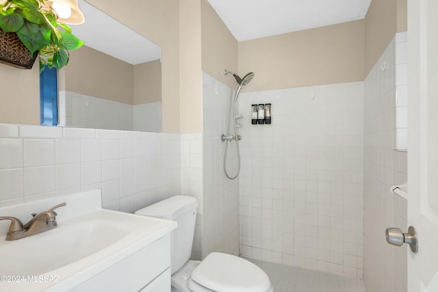 bathroom featuring a tile shower, vanity, toilet, and tile walls