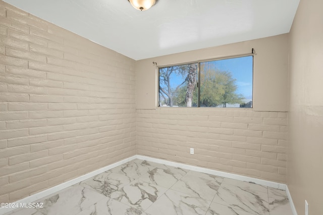 unfurnished room featuring brick wall