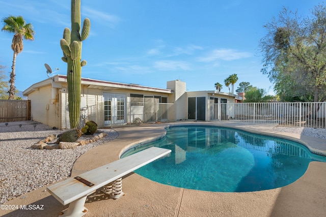 view of pool with a diving board and a patio