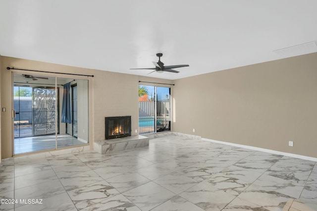 unfurnished living room featuring ceiling fan, a fireplace, and a wealth of natural light