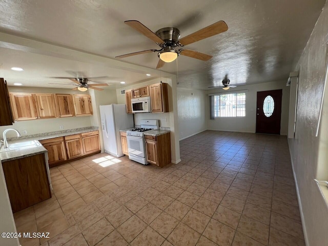 kitchen with sink, white appliances, light stone countertops, and light tile patterned floors