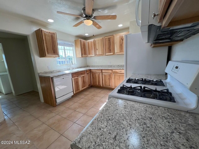 kitchen with light tile patterned floors, white appliances, sink, ceiling fan, and light stone countertops