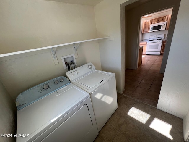 clothes washing area featuring dark tile patterned flooring and washing machine and dryer