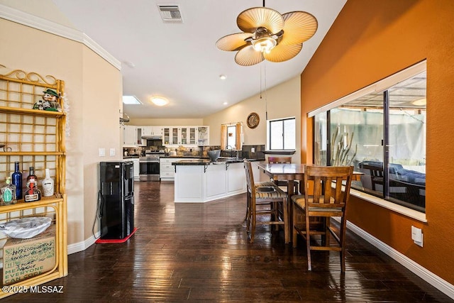 dining space with visible vents, baseboards, a ceiling fan, dark wood-style floors, and lofted ceiling