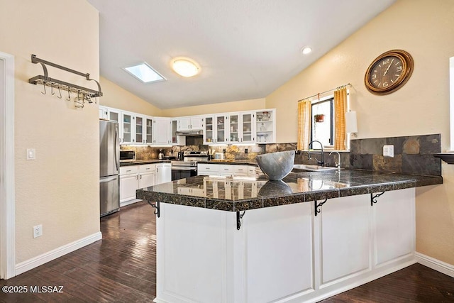 kitchen featuring stainless steel appliances, a peninsula, tile countertops, and lofted ceiling with skylight