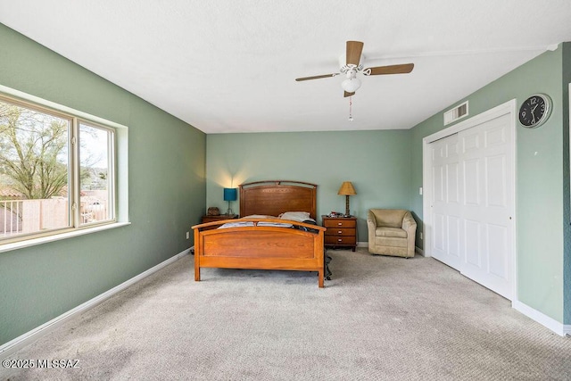 carpeted bedroom featuring visible vents, baseboards, a closet, and ceiling fan