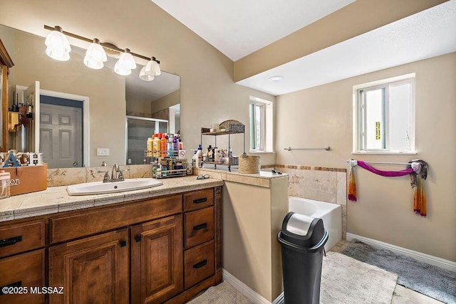 bathroom with vanity, baseboards, a stall shower, and a garden tub