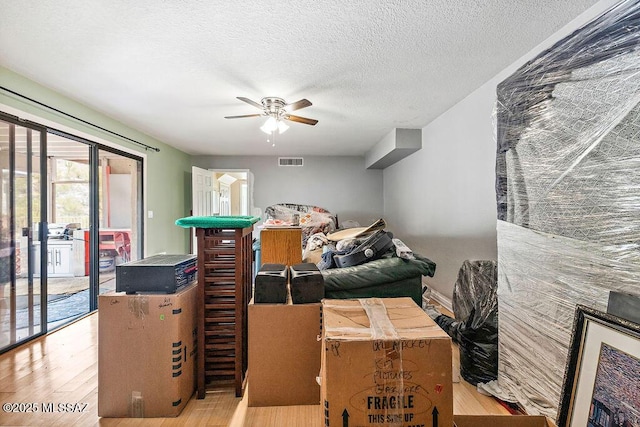 interior space with visible vents, a ceiling fan, wood finished floors, and a textured ceiling