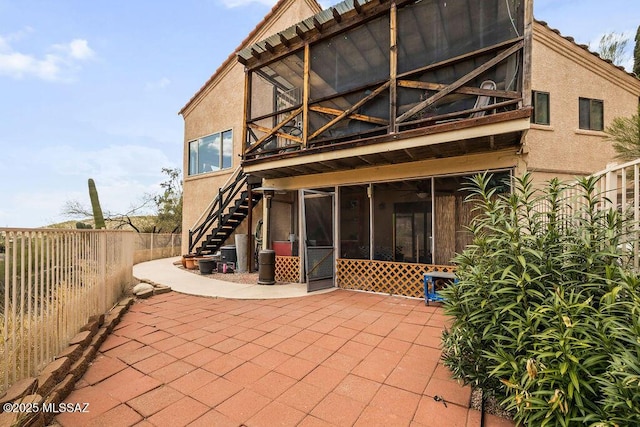 back of house featuring a sunroom, stucco siding, stairway, a patio area, and fence