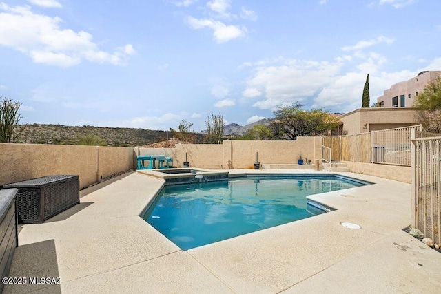 view of swimming pool featuring a fenced backyard, a pool with connected hot tub, and a patio