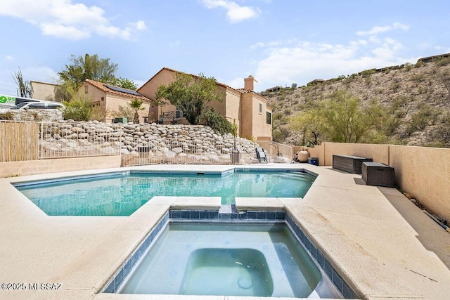 view of swimming pool with a pool with connected hot tub, a fenced backyard, and a patio area