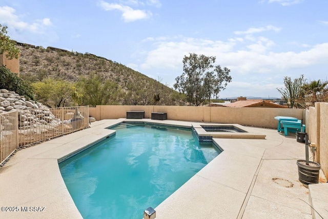view of pool featuring a fenced backyard, a pool with connected hot tub, and a patio