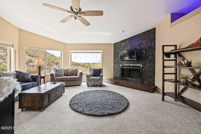 living room with plenty of natural light, a large fireplace, a ceiling fan, and carpet floors