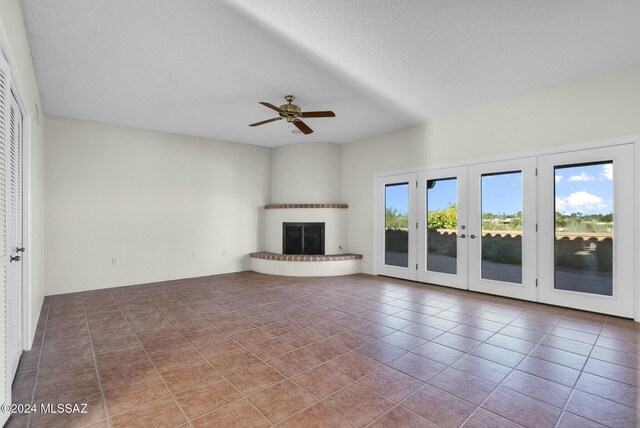 unfurnished living room with tile patterned floors, ceiling fan, and a textured ceiling